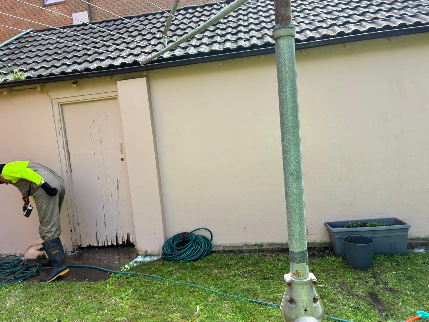 Gammy's team member pressure washing a heavily mould-stained garage wall and door